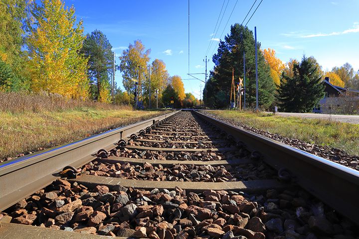 Järnvägsspår i höstlikt landskap.