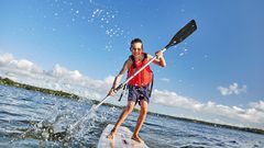 En glad pojke på en SUP-bräda.