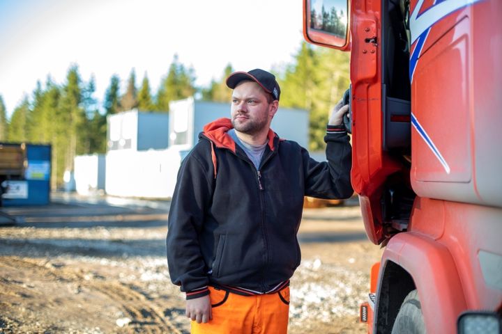 Ung man står vid lasbil och håller i förardörren.