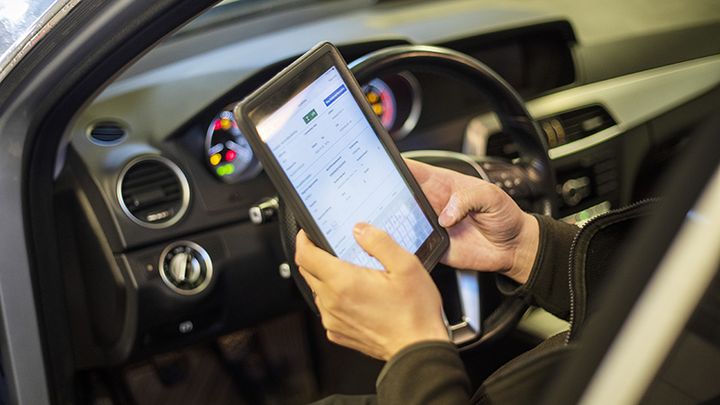 Händer som håller i en digital skärm för att registrera uppgifter under en kontrollbesiktning.