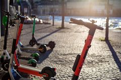 Alt text: Flera elsparkcyklar står parkerade på en stenbelagd trottoar vid vattnet.
