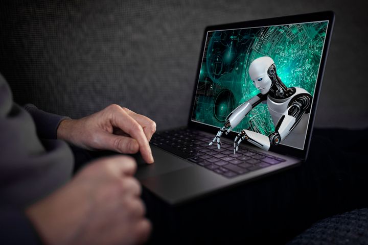 Robot sträcker sig ut från skärmen på en bärbar dator och skriver på tangetbordet.
