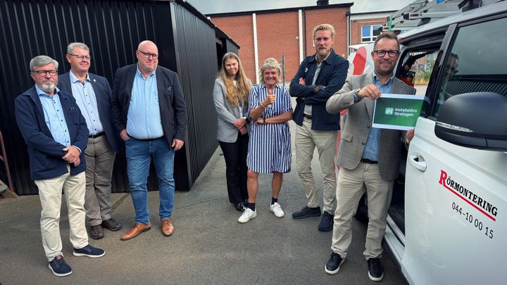 En grupp personer från VVS-firman Rörmontering i Kristianstad står bredvid en servicebil, medan en person håller upp ett A4-papper.