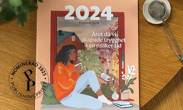 Bild på årsberättelsen på ett träbord med en stämpel från Publishingpriset att man är nominerad