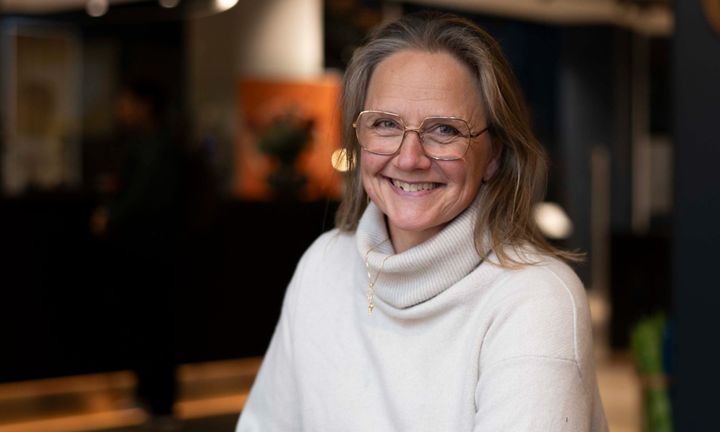 Bild på Caroline i vit polotröja mot mörk bakgrund