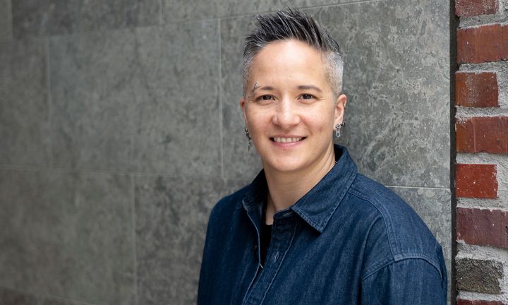 Alexandra Kaufmann i svart jeansskjorta framför en tegelvägg