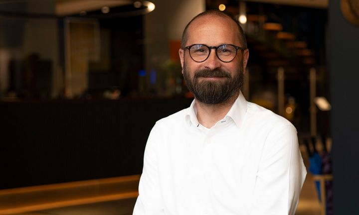 Bild på Mattias i vit skjorta mot mörk bakgrund