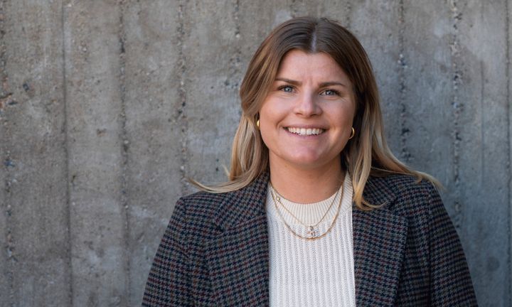 Bilöd på Ebba i vit tröja och svart kavaj framför en cementvägg