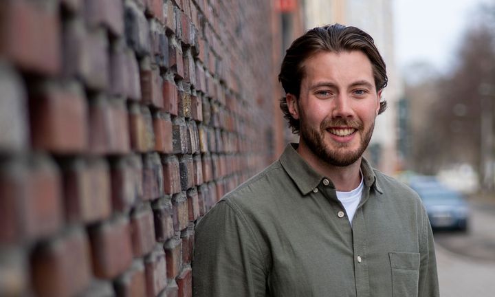 Bild på Filip iklädd grön skjorta utomhus mot en tegelmur