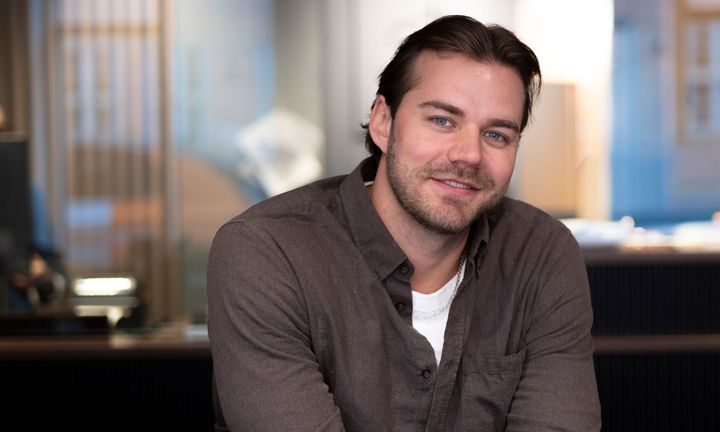 William fotad i en grå tröja med koncernens reception i bakgrunden