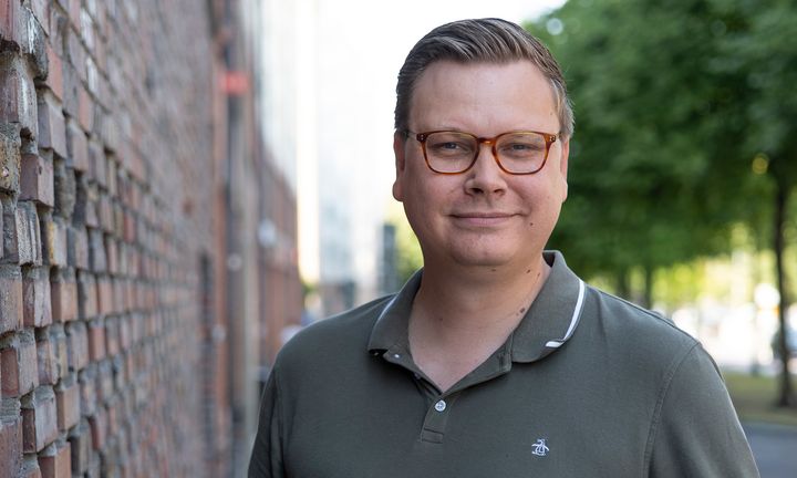 Bild på Max i grön pikétröja framför en mur utomhus