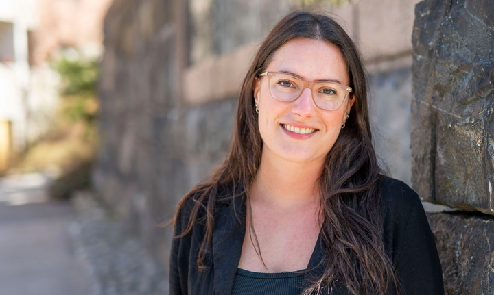 Emilia fotad i svart kavaj utomhus framför en stenvägg