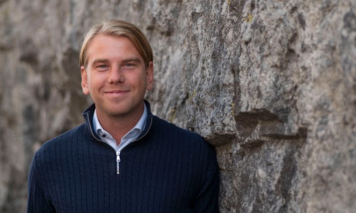 Bild på Lukas i svart tröja utomhus framför en grå stenvägg