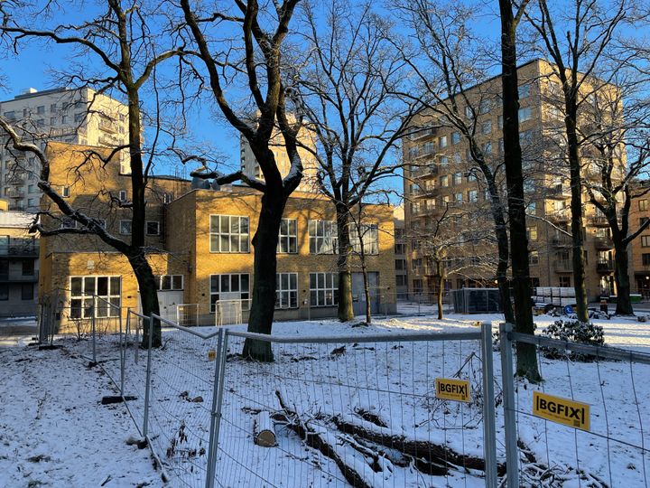 Kraftcentralen 2 sett från Ekparken i ett snölandskap med byggstängsel i förgrunden