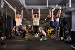 Personer tränar på gymmet genom att hänga i en stång och lyfta vikter.