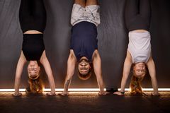 Tre personer gör handstående mot en vägg.