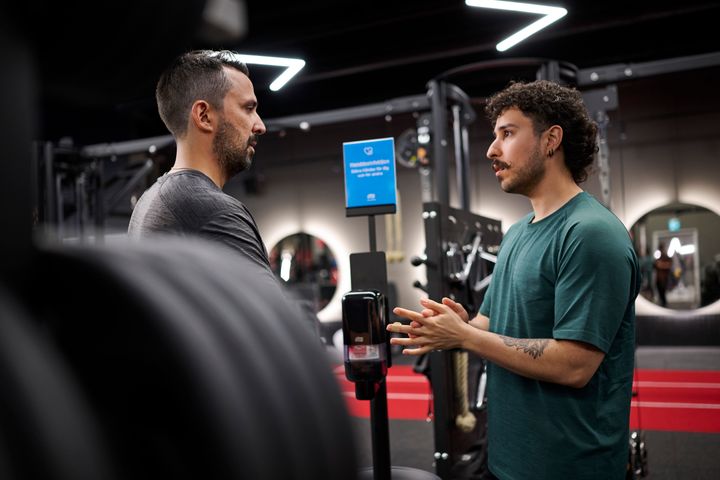 Två personer pratar med varandra på ett gym.