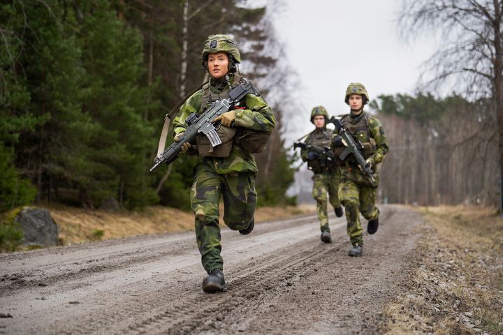 Värnpliktiga ungdomar som springer på en väg.