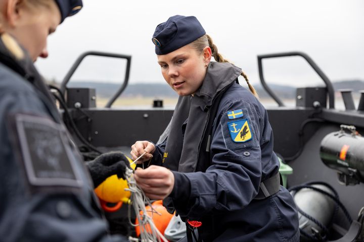 Två värnpliktiga kvinnor arbetar på en båt.