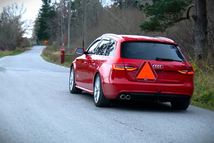 Röd Audi-kombi som A-traktor kör på en kurvig landsväg.