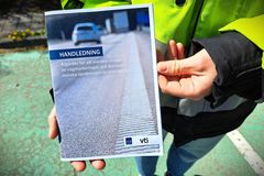 Person håller i en broschyr med text om åtgärder för att minska vägslitage och spridning av mikroplast.