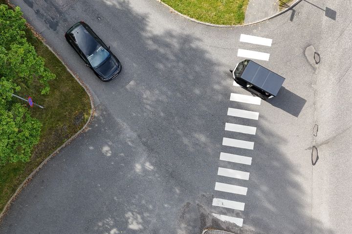 Flygbild av en korsning med ett lastfordon kallat EVIG, utrustat med solpaneler på taket, som korsar en övergångsställe.