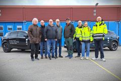 Grupp med människor framför två bilar.