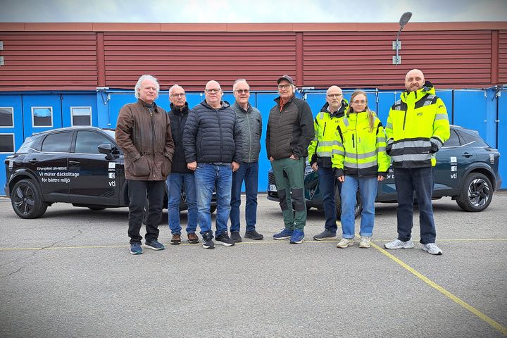 Grupp med människor framför två bilar.