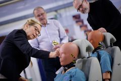 En kvinna och två män granskar krocktestdockor.