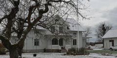 Två byggnader i form av bostadshus med snötäckta tak och trädgård.