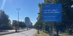 Del av Jordbrovägen sett från norr. En byggskylt finns i förgrunden med texten "Här blir vägen mer trafiksäker".