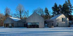 Snötäckt mark och blå himmel, tre byggnader i liknande former.