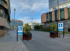 En väg (Brånebacken) med illustrationer i form av skyltar som visar gågata samt ett par större krukor med tallar i som markering på gatan.