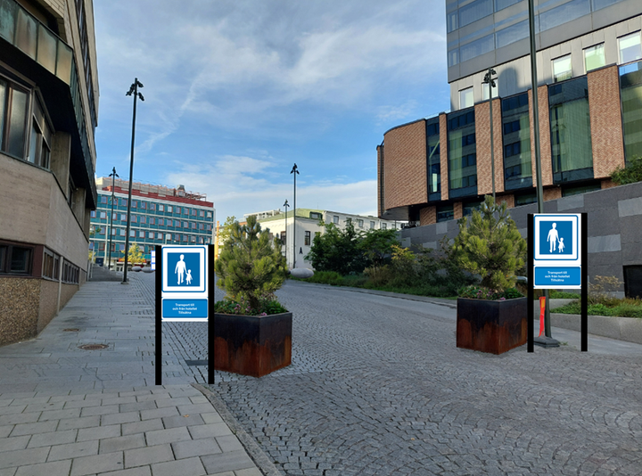 En väg (Brånebacken) med illustrationer i form av skyltar som visar gågata samt ett par större krukor med tallar i som markering på gatan.