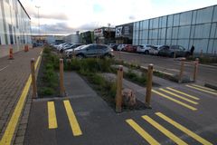En parkeringsyta med gröna inslag i ett handelsområde.