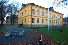 En stor, gul byggnad i äldre karaktär med många fönster och en grön parkyta framför.