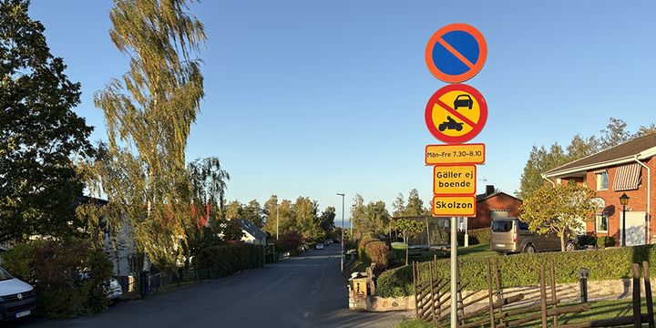vägskyltar i ett bostadsområde som visar att det är skolzon.