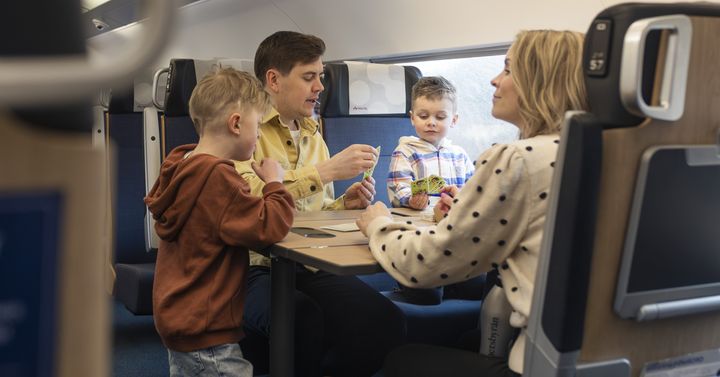 Familj samlad runt ett bord ombord på tåget och som spelar spel.