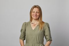 Halvkroppsporträtt på kvinna med långt blond hårt och grön blus.