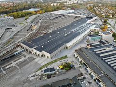 Översiktsbild ovanfrån över stora grå verkstadslokaler med tåg och spår.