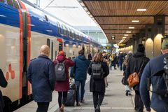 En tågperrong med många människor som går vid sidan av Mälartåg.