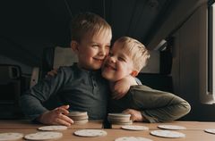 Två små pojkar busar och kramar varandra medan de spelar ett spel ombord på Mälartåg.
