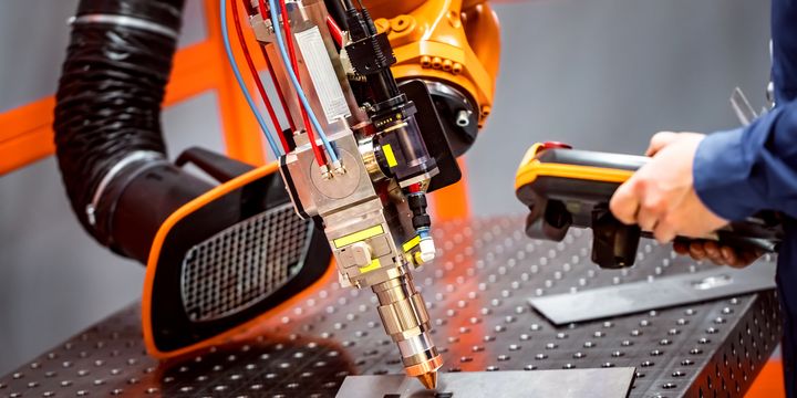 En industrirobotarm används för att utföra en teknikprocess på en metallplatta.