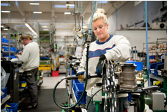 En person arbetar vid en stationär maskin i en fabrik.