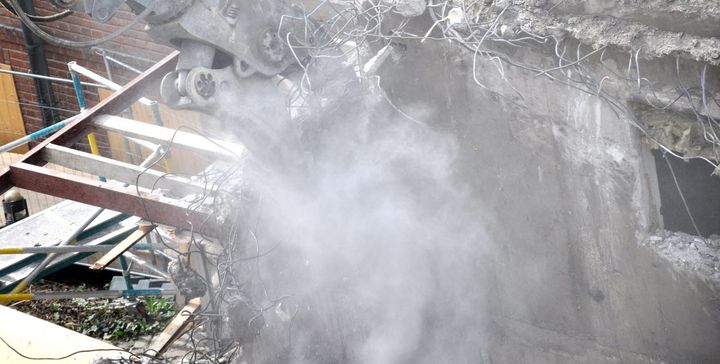 Byggarbetsplats där det rivs och skapar ett moln av stendamm.