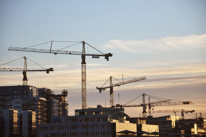 Byggkranar vid en byggarbetsplats i solnedgång.