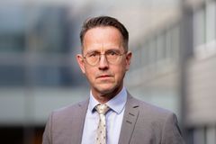 Porträtt av Arbetsmiljöverkets generaldirektör Lars Lööw i kostym och slips med glasögon, mot en suddig bakgrund av en byggnad.