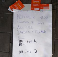 Vitt ark med påklistrade "Felanmäld"-märken i orange, text med kulspets i versaler säger "behöver hiss hänvisar vi att åka till Farsta strand buss 181 833 läge A 184 läge D".