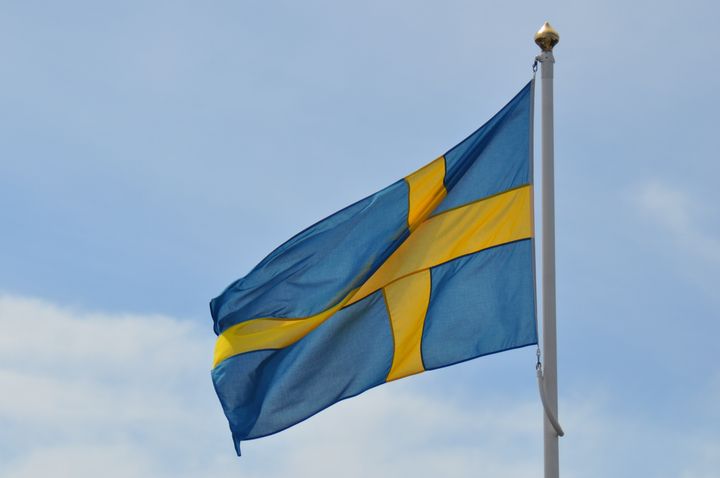 Den svenska flaggan vajar mot en blå himmel.