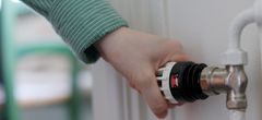 Hand vrider upp temperatur på termostat